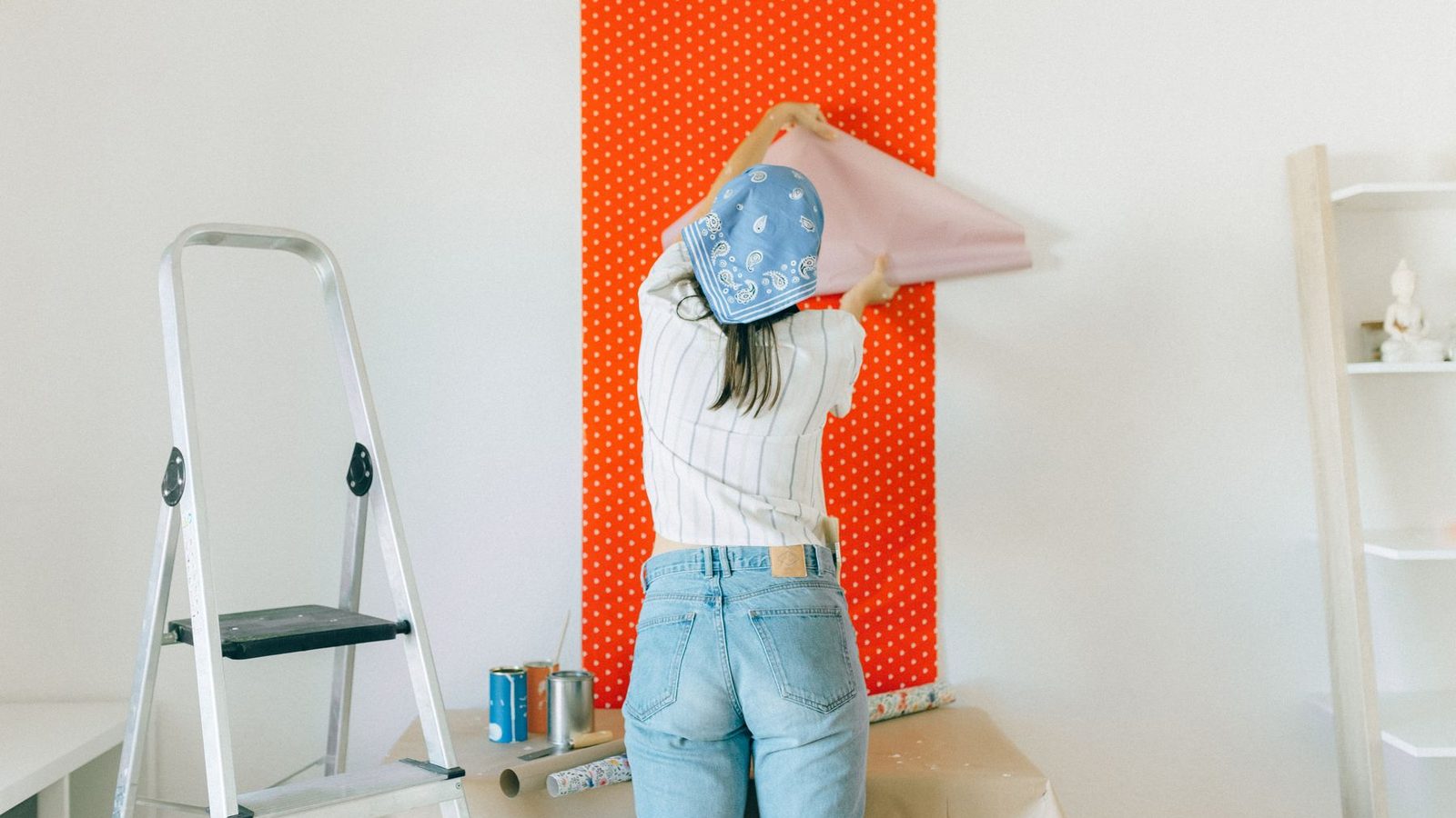 A person pressing a fresh strip of wallpaper onto a wall