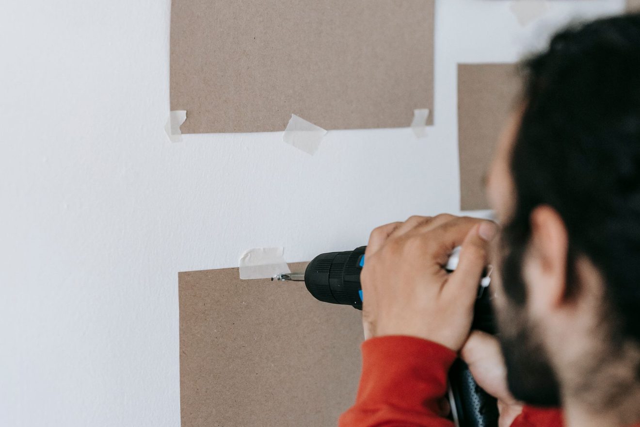 A person driving a screw into a wall to fix a panel