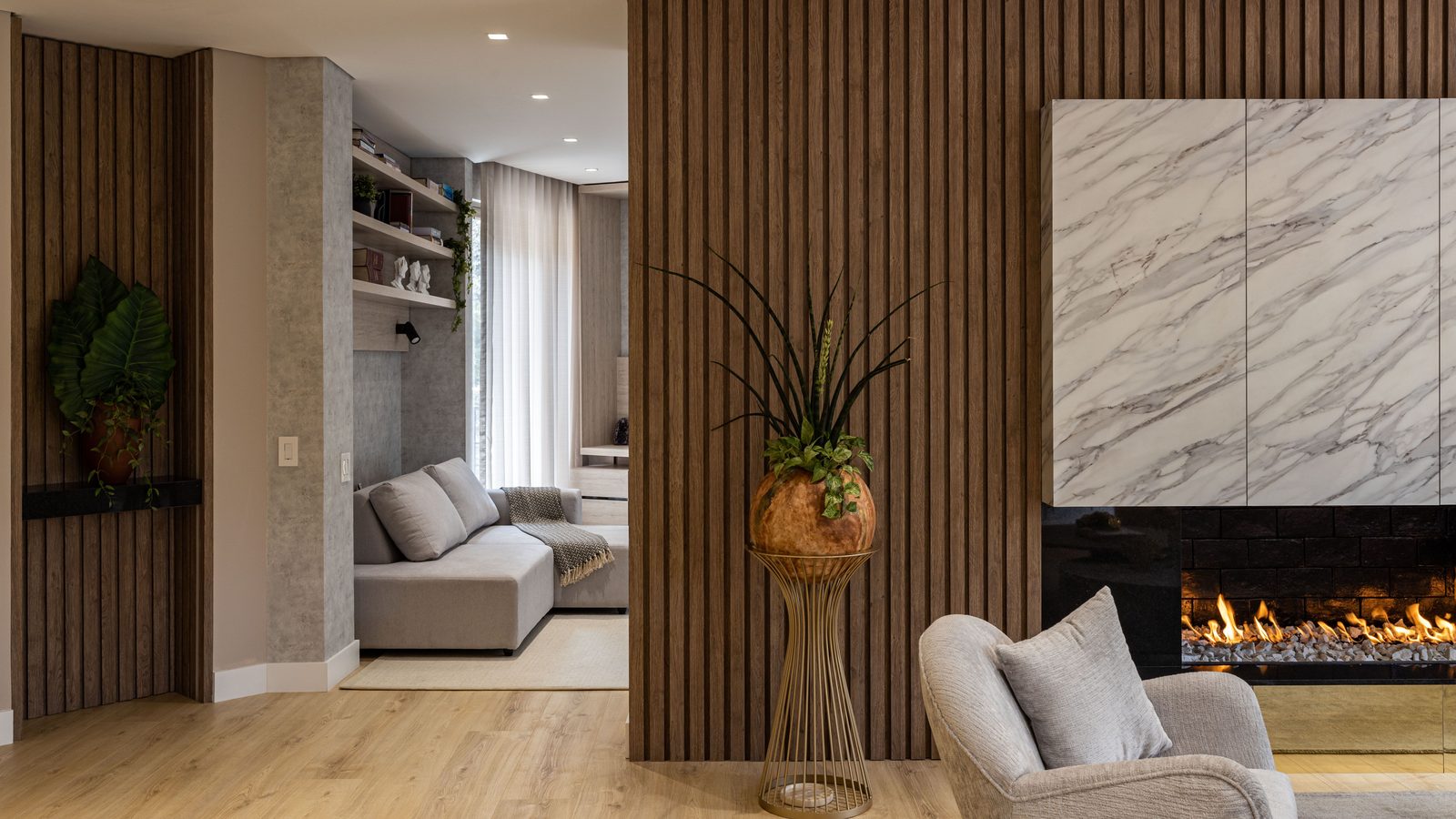 A living room with a vertical walnut slat feature wall beside a fireplace