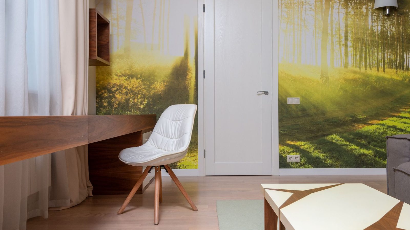 A study with a woodland mural wallpaper and a modern white chair