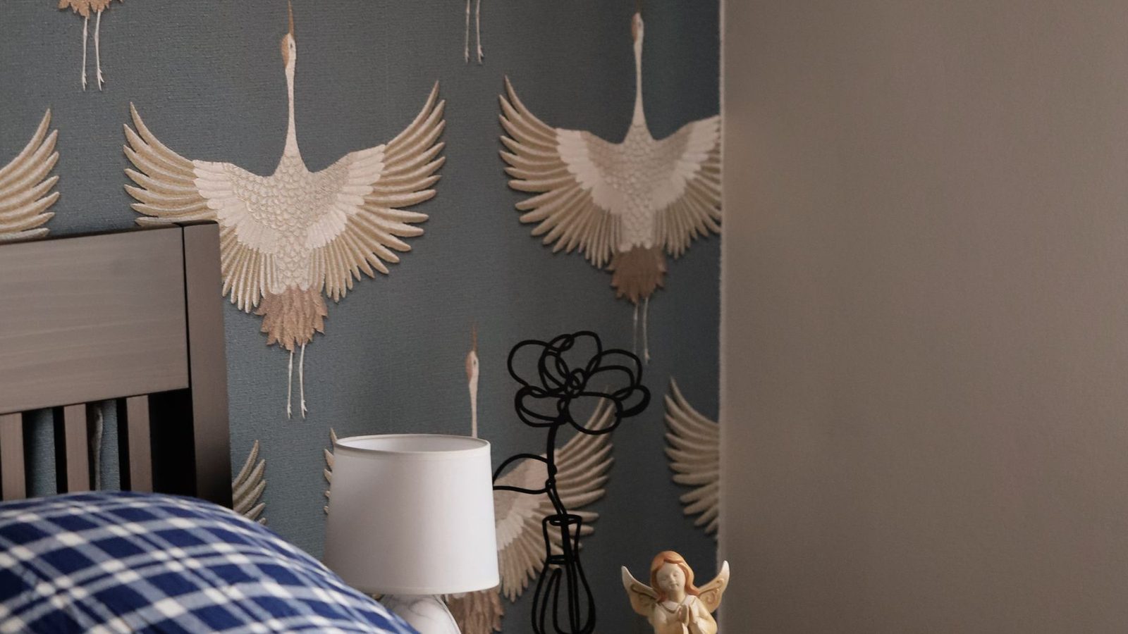 A bedroom with a bold crane-patterned wallpaper feature wall
