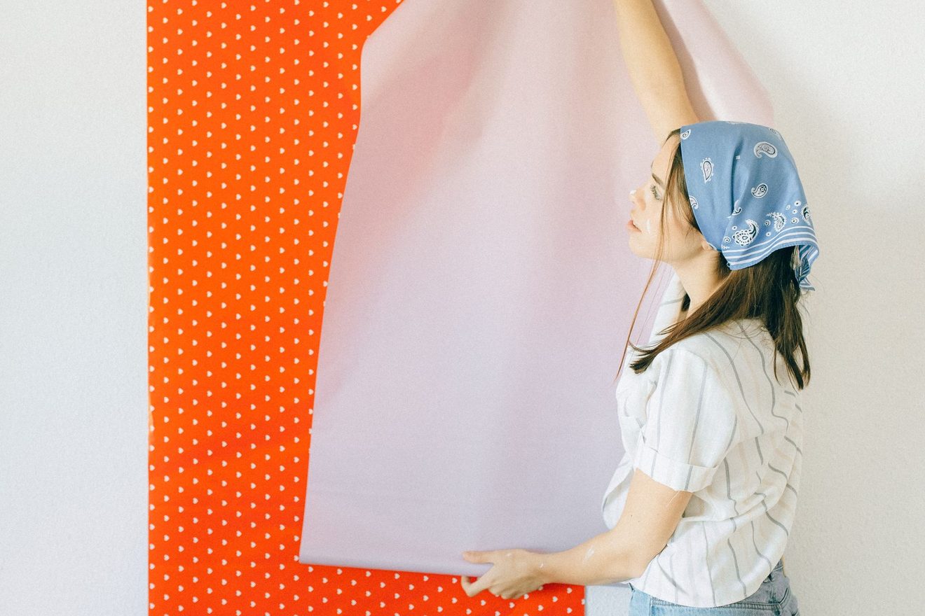 A person smoothing a strip of wallpaper onto a wall
